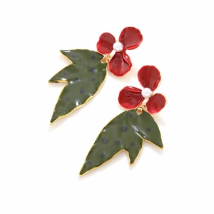 Detail of red enamel flower earrings with green polka dot leaves and faux pearl center