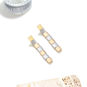 Makro-Detail von gestuften quadratischen Metall-Ohrhängern in Silber-Gold-Kontrastoptik