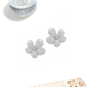 Detail of silver alloy flower earrings with textured petals and hammered finish style
