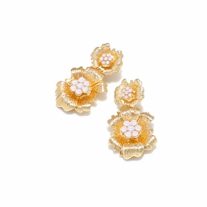 Detailed view of gold floral earrings with pleated metal petals and pearl centers
