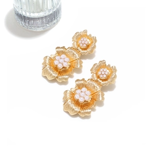 Detailed view of golden 3D flower earrings with ribbed petals and pearl centers