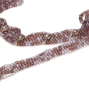 Detail of bohemian multilayered beaded necklace featuring purple faceted beads and rhinestones