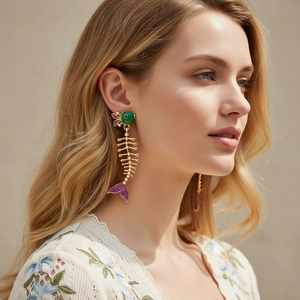 Detail of long fishbone drop earrings with purple fins and green enamel on a model