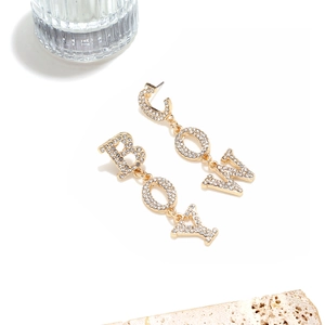 Detailed view of gold Cowboy rhinestone fringe earrings on white and marble background