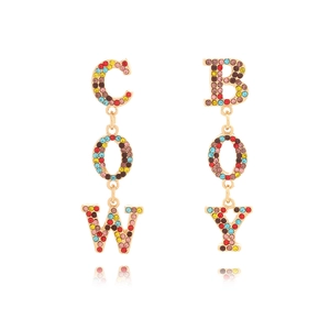 Detail of gold dangle earrings featuring multicolor rhinestones spelling COW BOY