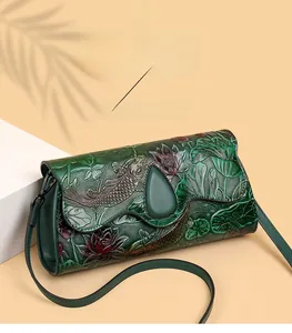Detail of green leather crossbody bag with traditional koi and lotus floral embossing