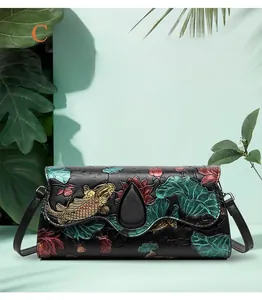 Detail of 3D embossed koi fish and lotus pattern on a black leather flap crossbody bag