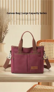 Détail d'un sac en toile bordeaux à poches multiples avec des sangles marron sur bois