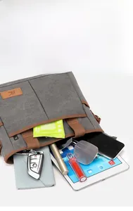 Détail du sac à bandoulière en toile grise avec compartiments pour tablettes et objets