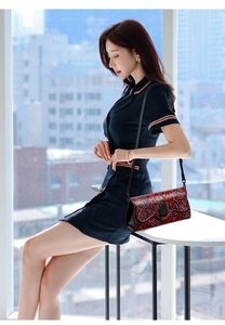 Detail of red floral embossed shoulder bag with black strap worn by a model
