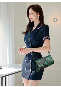 Close-up of green embossed leather bag with lotus and koi fish patterns and magnetic snap