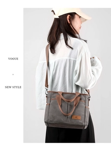 Sac bandoulière en toile grise avec lanières brunes et détail de poche frontale