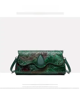 Detailed view of dark green crossbody bag featuring embossed koi and lotus flower patterns
