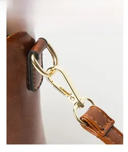 Détail du sac en cuir croco marron foncé montrant la bandoulière amovible dorée