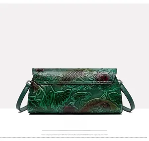 Detailed back view of an emerald green leather bag with embossed koi and lotus patterns
