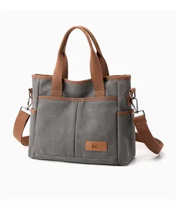 Détail d'un grand sac cabas en toile gris foncé avec anses brunes et logo en cuir