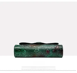 Detailed bottom view of a dark green crossbody bag with embossed fish and lotus leaf patterns