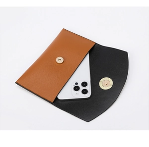 Dettaglio della borsa a secchiello in pelle marrone con doppia chiusura magnetica dorata