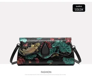 Detailed close-up of embossed goldfish and lotus patterns on a black leather handbag