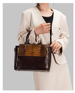 Détail du sac à main marron en cuir crocodile avec des finitions zippées dorées