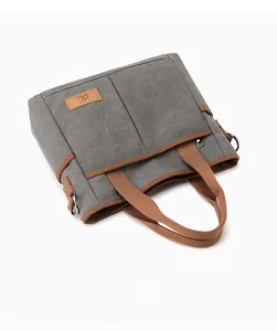 Détail d'un grand sac cabas en toile avec poignées brunes et patch en cuir