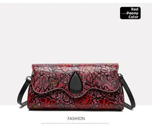 Detail of red peony floral embossing and hardware on a vintage crossbody bag