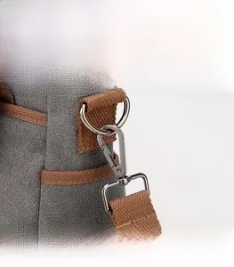 Détail du sac en toile gris foncé montrant le crochet en métal et la sangle brune