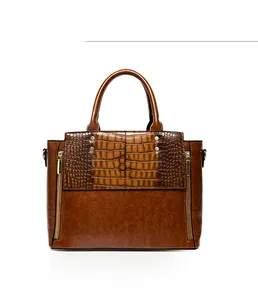 Détail du sac à main en similicuir marron avec motif crocodile et double zip doré