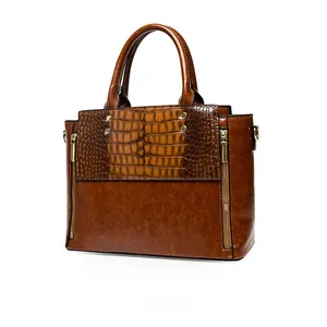 Détail d'un sac à main marron en simili cuir avec motif crocodile et fermetures éclair dorées