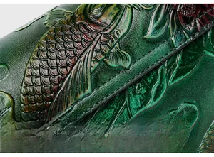 Detail of embossed koi fish pattern on green leather bag with precision stitching