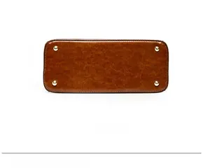 Détail du fond du sac en cuir marron avec quatre pieds de protection en métal doré