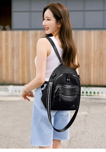 Detail of black pebbled leather backpack with zipper pockets and stylish arrow strap