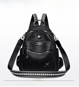 Detail of black pebbled leather backpack featuring silver zippers and woven shoulder strap