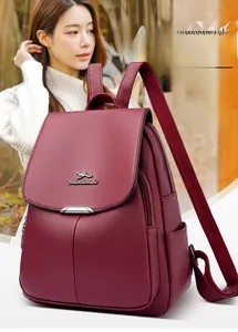 Detail of burgundy lychee-grain faux leather backpack with kangaroo metal logo plaque