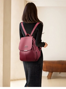 Macro view of burgundy lychee grain faux leather backpack with metallic logo detail