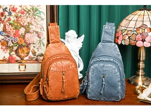 Close-up of vintage washed leather chest bags in brown and blue with multi-pocket detail