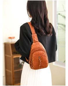 Brown leather crossbody chest bag shown on model with vintage texture and multiple zippers