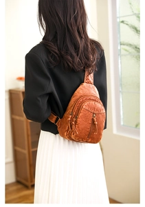 Detail view of dark brown vintage leather chest bag with zipper pockets and tassels