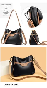 Detailed view of black litchi leather crossbody bag with brown trim and dual strap options
