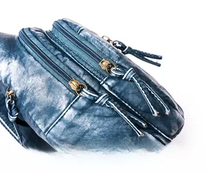 Detailed macro view of smooth dual metal zippers on vintage blue leather sling bag