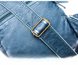 Detail of adjustable blue PU leather strap with vintage metal buckle and litchi texture