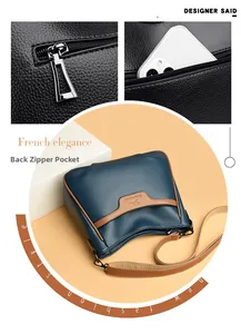 Detail view of the back zipper pocket on the blue leather crossbody bag with logo