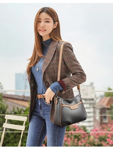 Close-up of black litchi texture leather crossbody bag with brown contrast trim and logo