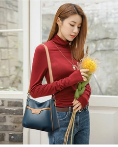 Detail of navy blue pebble leather crossbody bag with brown trim and kangaroo logo