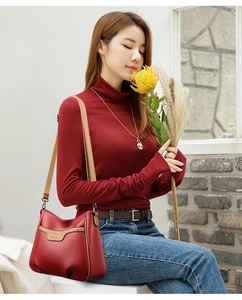 Close-up of red pebbled leather crossbody bag with brown trim and kangaroo logo detail
