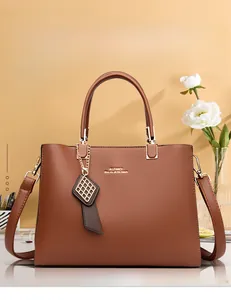 Gros plan détaillé d'un sac à main marron en similicuir avec logo et breloque en métal