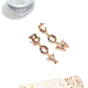 Detailed macro of gold long dangle cowboy earrings featuring colorful rhinestones