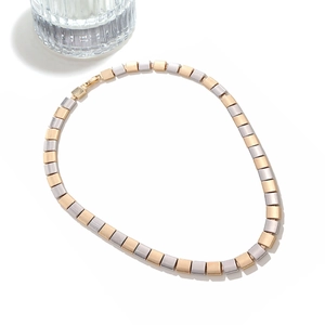 Macro shot of two-tone gold and silver square metal tiles on a chunky geometric necklace