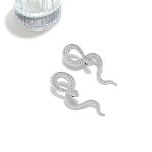 Détail de boucles d'oreilles serpent argentées avec écailles et yeux en pierres noires