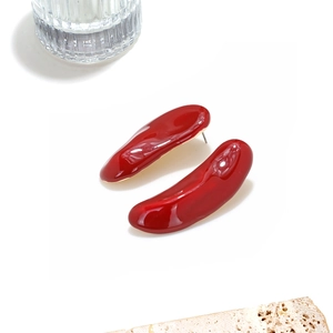 Gros plan de boucles d'oreilles émaillées rouges asymétriques avec base en métal doré